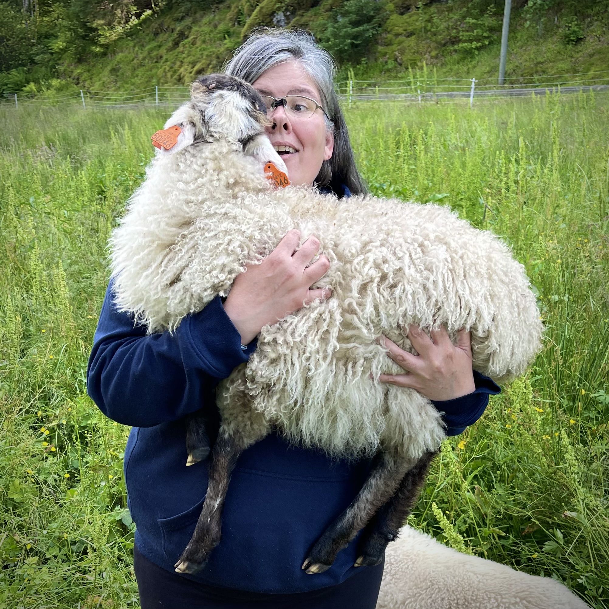 Aubrey, a woman, holding a young sheep in her arms.